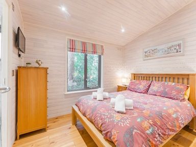 a bedroom with a wooden bed and towels on it at Kelling Heath Holiday Park - Holiday Accommodation 18691 Holt