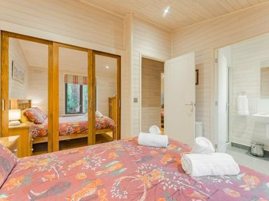 a bedroom with a large bed, mirrored wardrobe, and an adjoining bathroom at Kelling Heath Holiday Park - Holiday Accommodation 18691, Holt