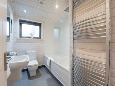 a bathroom with a bathtub, toilet, and towel warmer at Kelling Heath Holiday Park - Holiday Accommodation 18691 in Holt