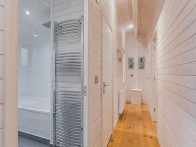 a hallway with wooden flooring and white paneling at Kelling Heath Holiday Park - Holiday Accommodation 18691 in Holt