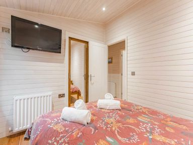 a bedroom with a double bed and a television on the wall at Kelling Heath Holiday Park - Holiday Accommodation 18691, Holt