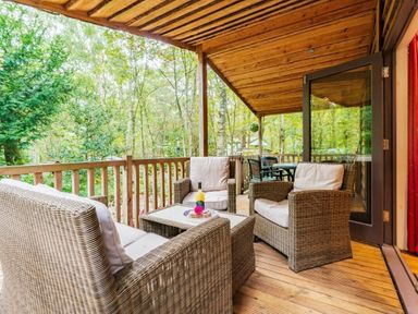 a balcony with seating and tables surrounded by trees at Kelling Heath Holiday Park - Holiday Accommodation 18691 in Holt