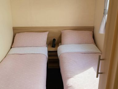 A bedroom with two beds and a bedside table at Golden Gate Holiday Centre - Holiday Accommodation 19059 in Towyn