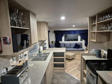 A kitchen with appliances and a living area at Presthaven Beach Resort - Holiday Accommodation 19166, Prestatyn