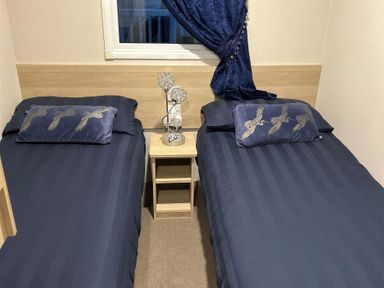 A bedroom with two single beds and a bedside table at Presthaven Beach Resort - Holiday Accommodation 19166, Prestatyn