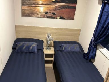 A bedroom with two twin beds and a bedside table at Presthaven Beach Resort - Holiday Accommodation 19166, Prestatyn