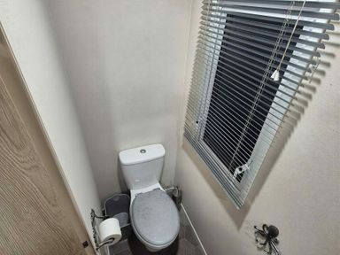 A bathroom with a toilet and window at Presthaven Beach Resort - Holiday Accommodation 19166 Prestatyn