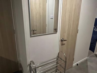 A hallway with a mirror and a clothes rack at Presthaven Beach Resort - Holiday Accommodation 19166, Prestatyn