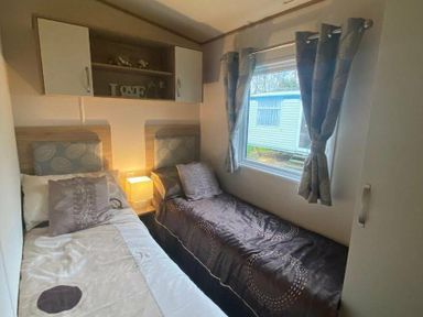 a bedroom with two beds, a window, and shelves at Butlins Skegness - Holiday Accommodation 19332 in Skegness