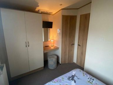 a bedroom with a wardrobe, mirror, and a small table at Butlins Skegness - Holiday Accommodation 19332 in Skegness