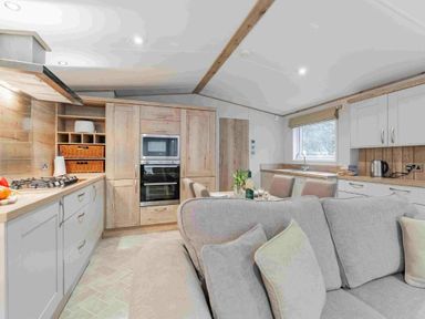 a kitchen with wooden cabinets and modern appliances at Kelling Heath Holiday Park - Holiday Accommodation 19669, Holt