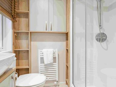 a bathroom with a shower, toilet, and shelving at Kelling Heath Holiday Park - Holiday Accommodation 19669 in Holt