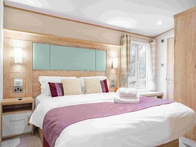 a bedroom with a bed, pillows, and a window at Kelling Heath Holiday Park - Holiday Accommodation 19669, Holt