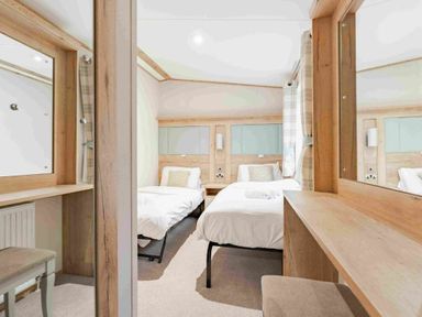 a bedroom with two beds and a vanity table at Kelling Heath Holiday Park - Holiday Accommodation 19669 in Holt