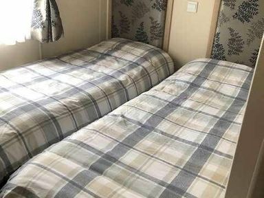 a bedroom with two single beds covered in checkered bedding at Pinewoods Holiday Park - Holiday Accommodation 19734 in Wells-Next-The-Sea
