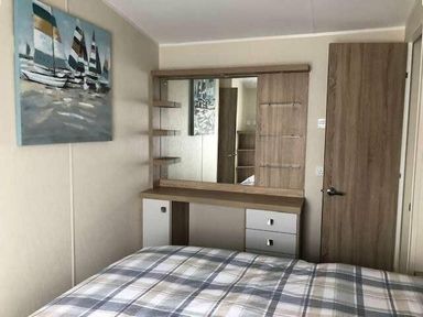 a bedroom with a bed and a dressing table with a mirror at Pinewoods Holiday Park - Holiday Accommodation 19734, Wells-Next-The-Sea