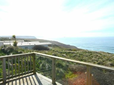 a view of the ocean and cliffs from a wooden deck at Perran Sands - Holiday Accommodation 19778 in Perranporth