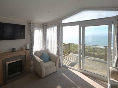 a living room with a fireplace and sea view at Perran Sands - Holiday Accommodation 19778 Perranporth