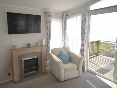 a sitting area with a television, fireplace, and chair at Perran Sands - Holiday Accommodation 19778, Perranporth