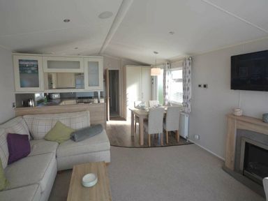 a living room and dining area with a sofa and table at Perran Sands - Holiday Accommodation 19778 in Perranporth