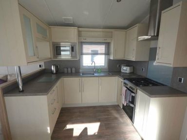 a kitchen with cabinets, a sink, stove, and microwave at Perran Sands - Holiday Accommodation 19778 in Perranporth