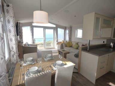 a living area with a dining table and ocean view at Perran Sands - Holiday Accommodation 19778, Perranporth