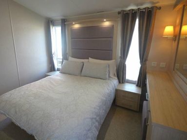 a bedroom with a large bed, bedside tables, and a dresser at Perran Sands - Holiday Accommodation 19778, Perranporth