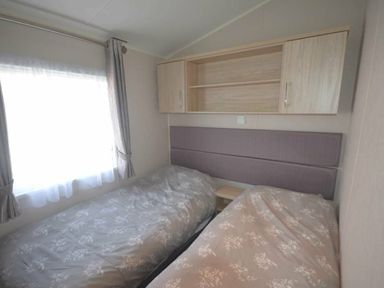 a bedroom with two single beds and a shelf above at Perran Sands - Holiday Accommodation 19778 in Perranporth