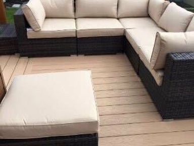 a sectional outdoor sofa with beige cushions on a wooden deck at Hafan y Mor Haven - Holiday Accommodation 19898 Pwllheli