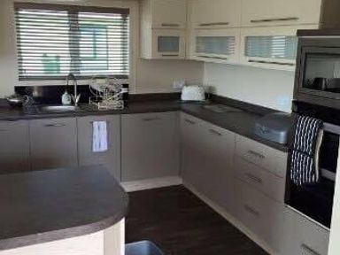 a kitchen with cabinets, countertop, and appliances at Hafan y Mor Haven - Holiday Accommodation 19898 in Pwllheli