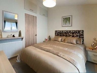 a bedroom with a double bed and decorative headboard at Hafan y Mor Haven - Holiday Accommodation 19898 in Pwllheli