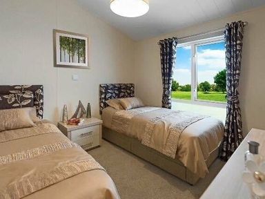 a bedroom with two single beds and a window overlooking greenery at Hafan y Mor Haven - Holiday Accommodation 19898 Pwllheli