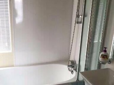 a bathroom featuring a bathtub and a shower with glass enclosure at Hafan y Mor Haven - Holiday Accommodation 19898 in Pwllheli