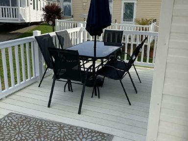 a outdoor dining set with a table and chairs on a wooden deck at Lyons Moelfre View - Holiday Accommodation 20226, Talybont