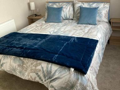 a bed with a patterned duvet and blue pillows at Lyons Moelfre View - Holiday Accommodation 20226, Talybont