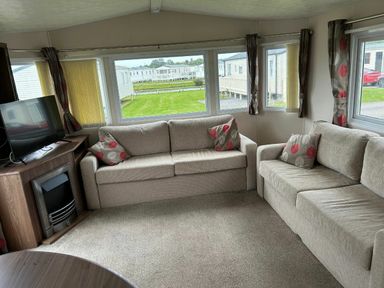 a seating area with two sofas and a television in a holiday caravan at Sand Le Mere Holiday Village - Holiday Accommodation 20326, Tunstall