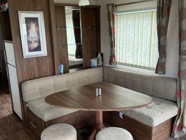 a dining area with a round table and corner seating at Sand Le Mere Holiday Village - Holiday Accommodation 20326 in Tunstall