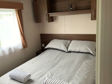 a bedroom with a double bed and shelves at Sand Le Mere Holiday Village - Holiday Accommodation 20326 in Tunstall