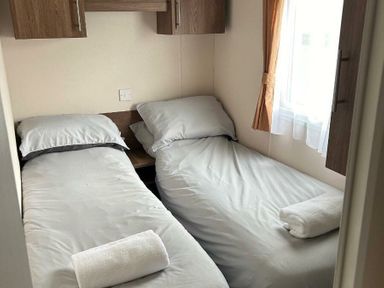 a small bedroom with two single beds and a window at Sand Le Mere Holiday Village - Holiday Accommodation 20326 in Tunstall