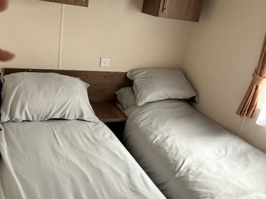a bedroom with two single beds and a wooden bedside table at Sand Le Mere Holiday Village - Holiday Accommodation 20326 in Tunstall