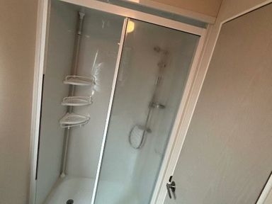 a shower enclosure with sliding doors and built-in shelves at Sand Le Mere Holiday Village - Holiday Accommodation 20326 in Tunstall