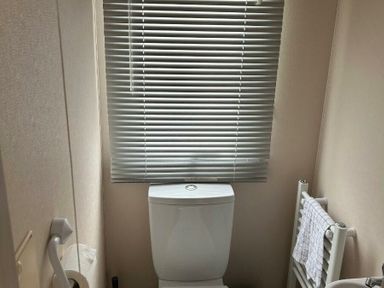 a bathroom with a toilet and blinds at Sand Le Mere Holiday Village - Holiday Accommodation 20326, Tunstall