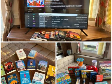 a television displaying a schedule surrounded by various DVDs and books at Sand Le Mere Holiday Village - Holiday Accommodation 20326 in Tunstall