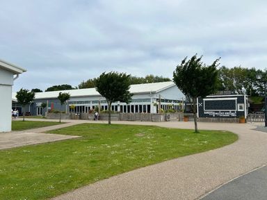 a building with large windows surrounded by grass and trees at Sand Le Mere Holiday Village - Holiday Accommodation 20326, Tunstall
