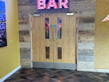 a set of wooden double doors with glass panels leading to a bar at Sand Le Mere Holiday Village - Holiday Accommodation 20326 Tunstall