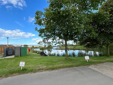 a landscaped area with a pond and trees at Sand Le Mere Holiday Village - Holiday Accommodation 20326, Tunstall