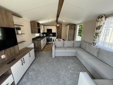 a living room with a sectional sofa and kitchen in Hafan y Mor Haven - Holiday Accommodation 20481 Pwllheli