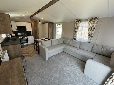 a lounge area with a gray sectional sofa and a small dining table at Hafan y Mor Haven - Holiday Accommodation 20481, Pwllheli