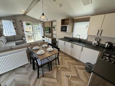 a dining area with a table set for four and a kitchen in Hafan y Mor Haven - Holiday Accommodation 20481 Pwllheli