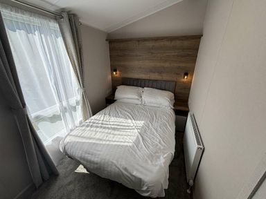 a bedroom with a bed, nightstands, and curtains at Hafan y Mor Haven - Holiday Accommodation 20481 Pwllheli